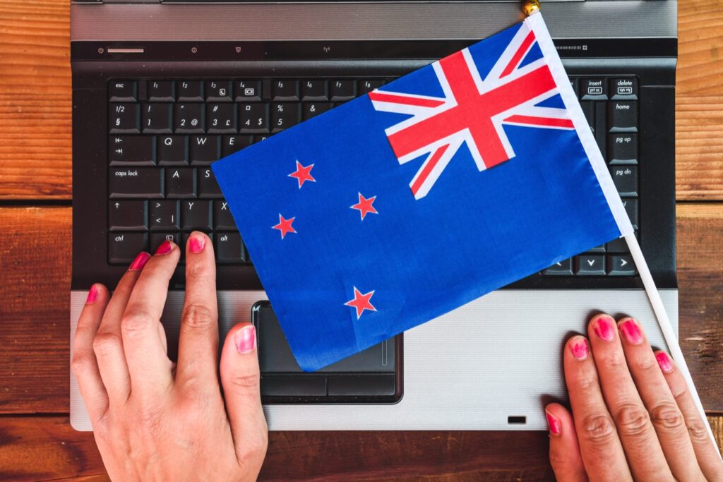 Business owner working on a WordPress website with a New Zealand flag resting on the laptop keyboard
